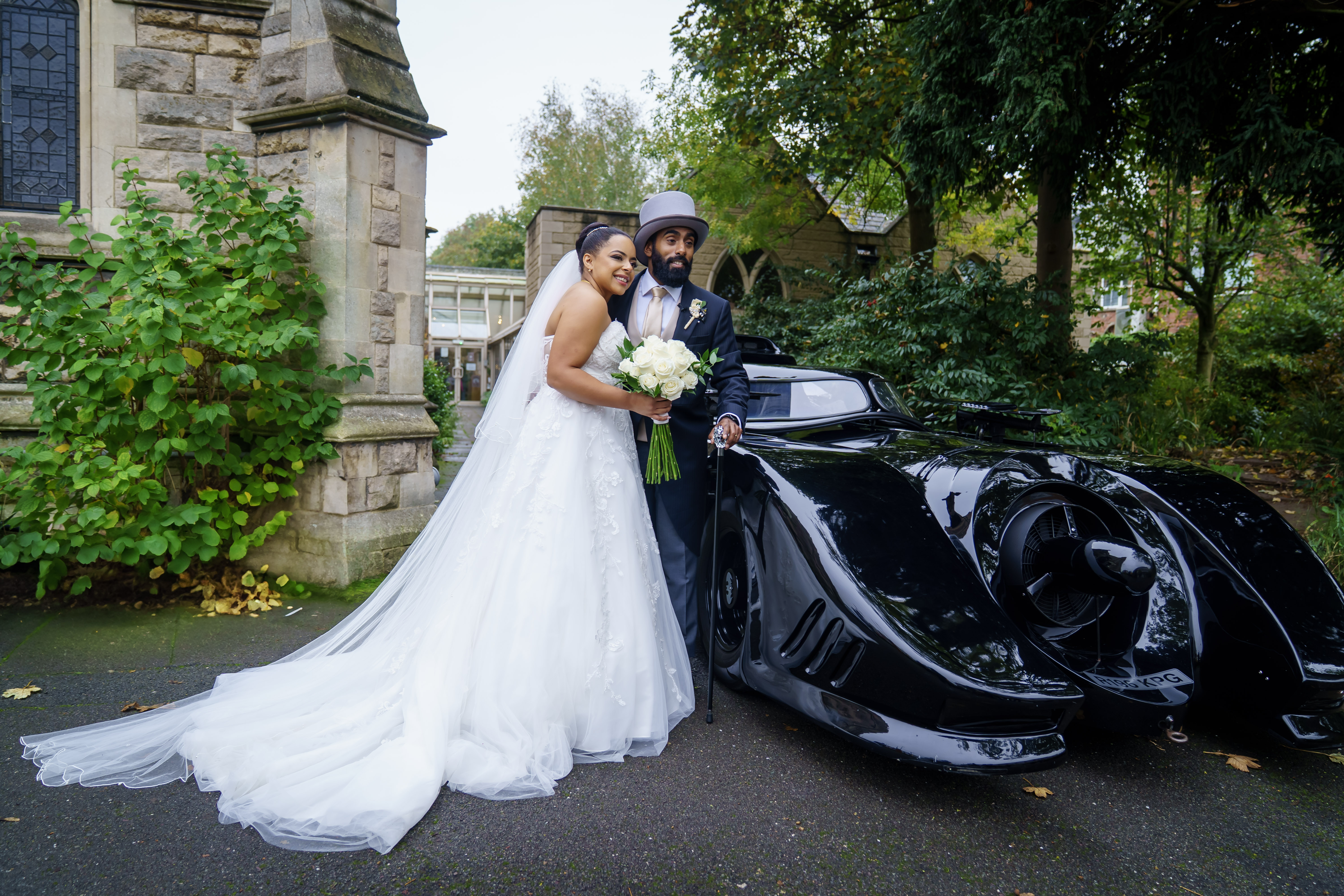 Newlyweds standing beside a classic car