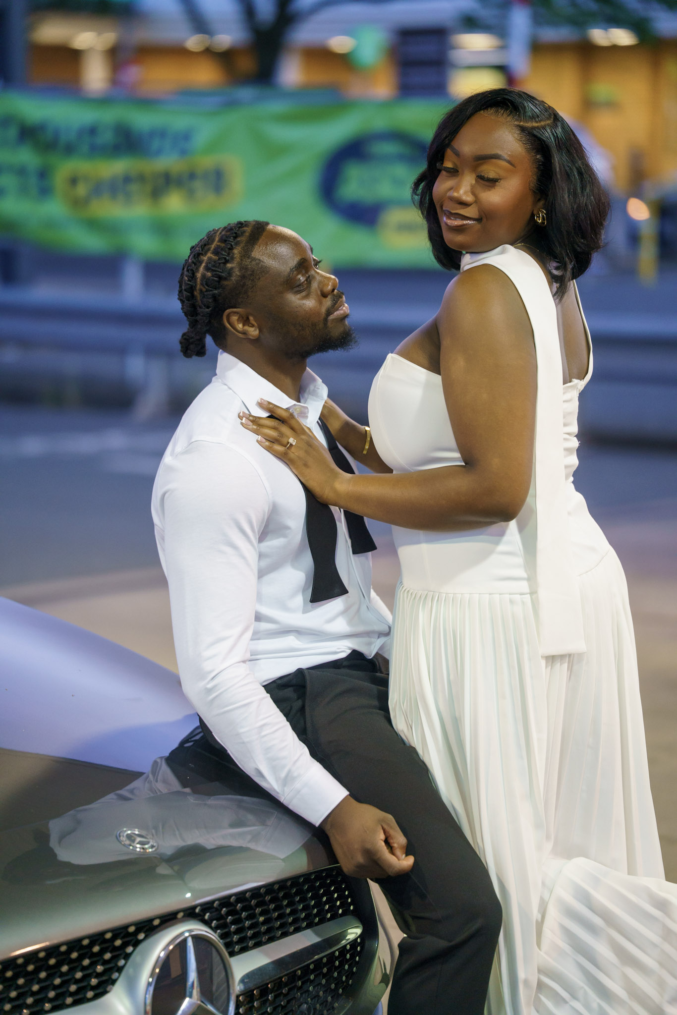 Bride and groom posing together beside a car