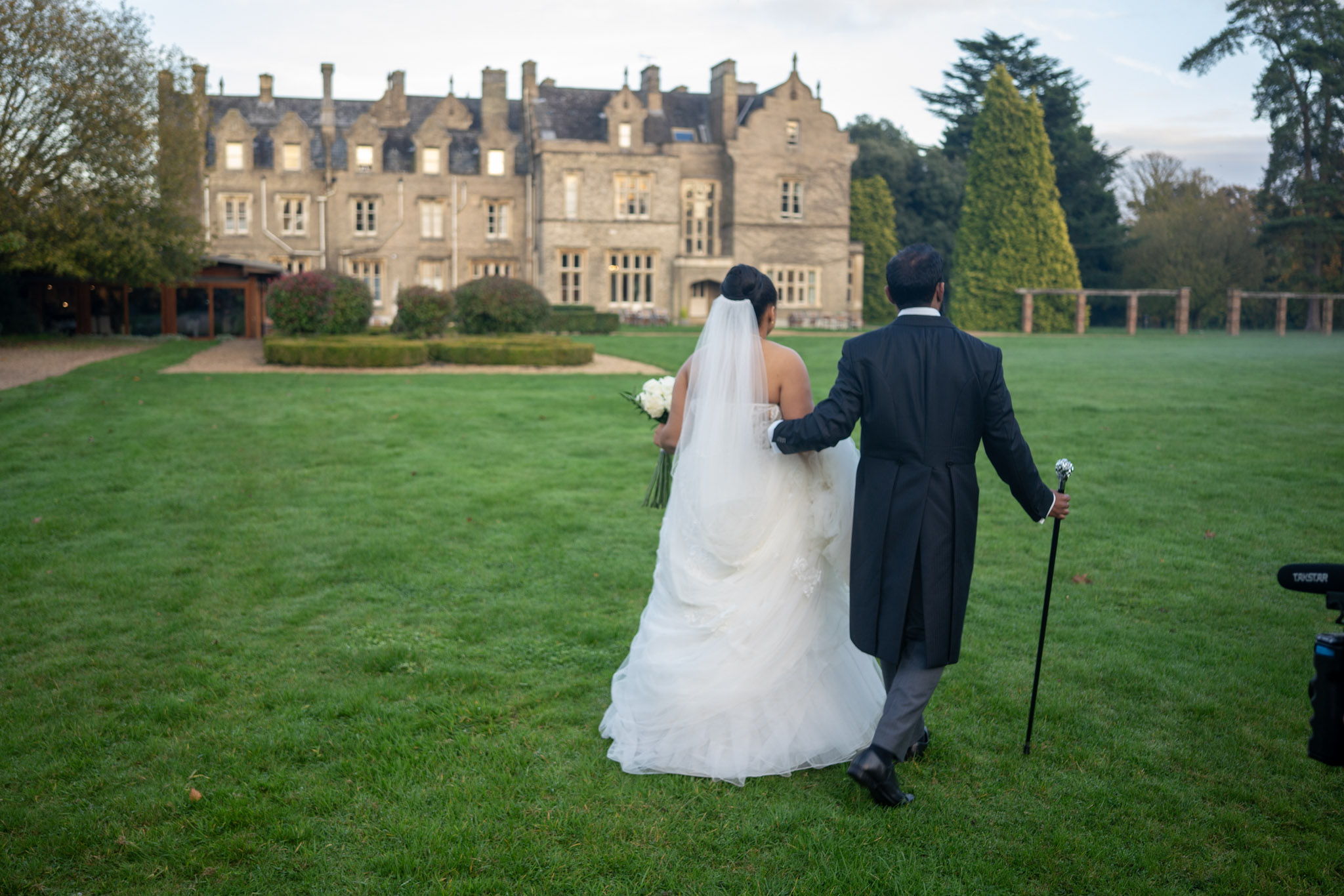 Bride and groom walking across a lawn